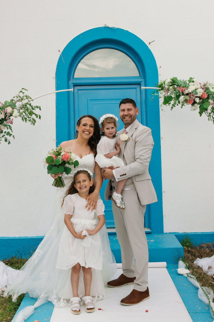 Outdoors island wedding ceremony, editorial photography, destination wedding at Agios Stephanos, Kastri island in KOS, Greece. Blue and white chapel. Family photo.