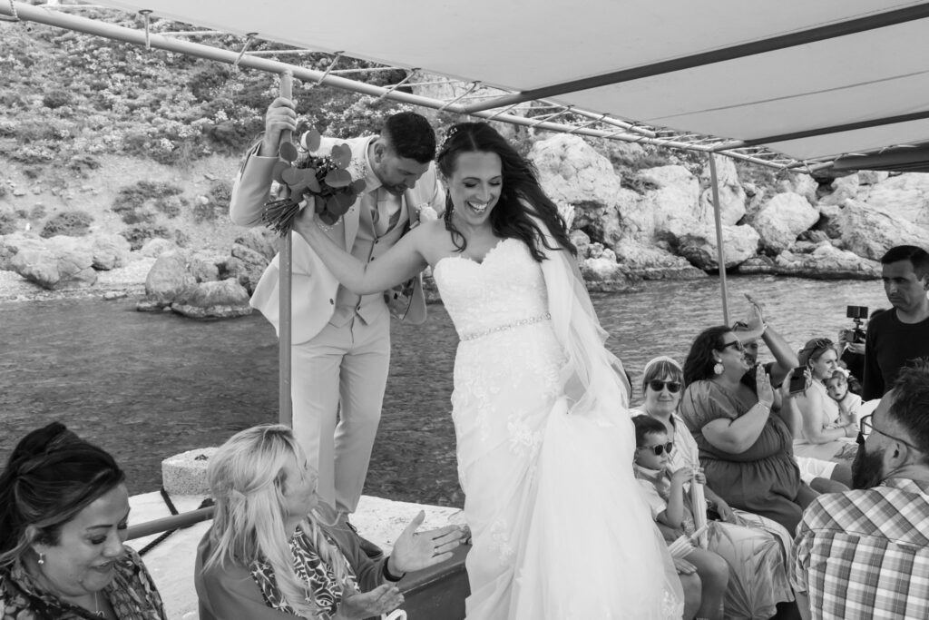 Outdoors island wedding ceremony, editorial photography, destination wedding at Agios Stephanos, Kastri island in KOS, Greece. Bride and groom getting into the boat.
