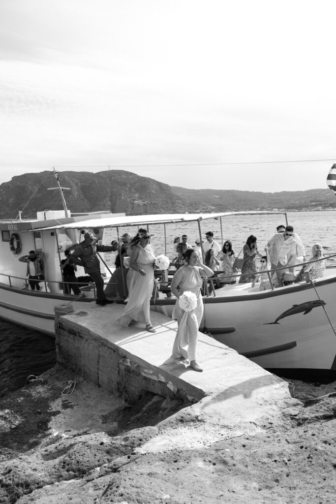 Wedding guests arriving by boat for outdoors island wedding ceremony, editorial photography, destination wedding at Agios Stephanos, Kastri island in KOS, Greece.