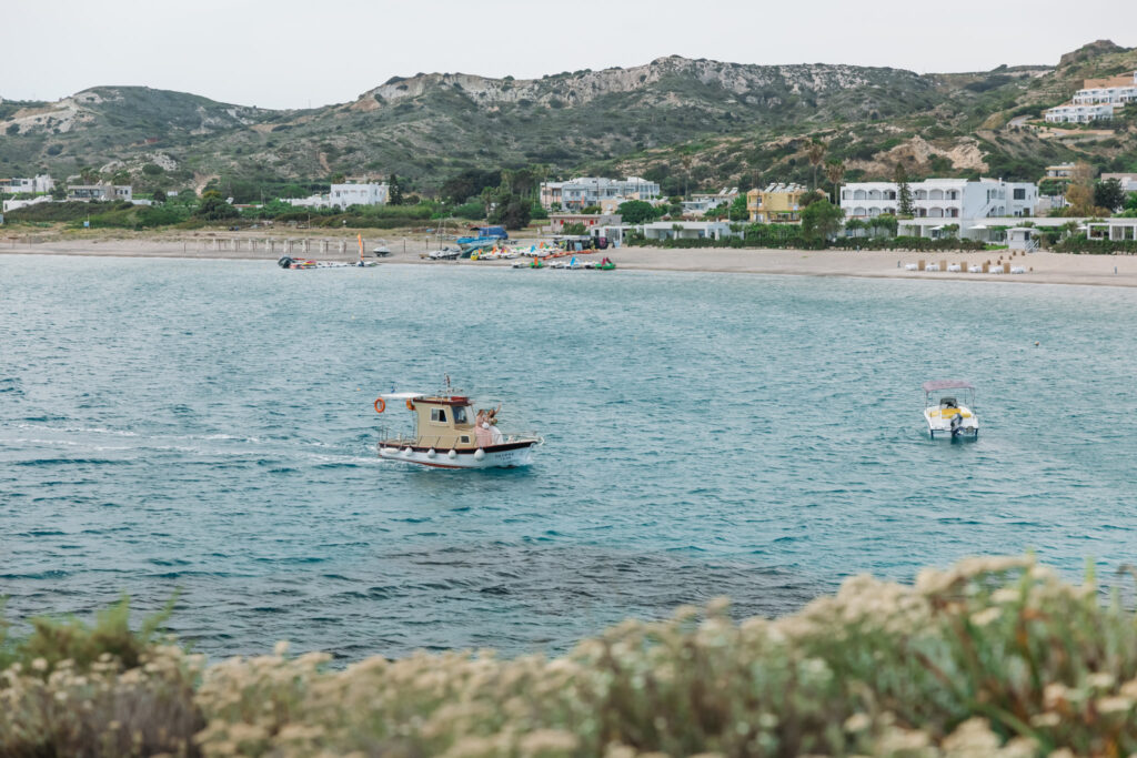 Bride arriving to the island by boat, editorial photography, destination wedding at Agios Stephanos, Kastri island in KOS, Greece.