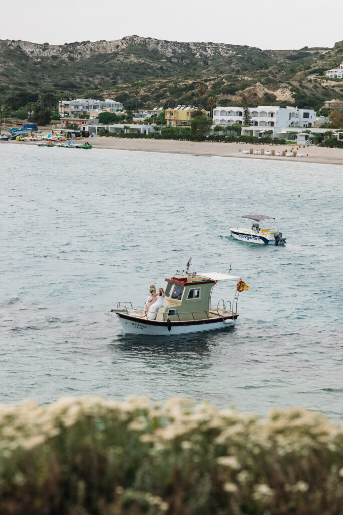 Bride arriving to the island by boat, editorial photography, destination wedding at Agios Stephanos, Kastri island in KOS, Greece.