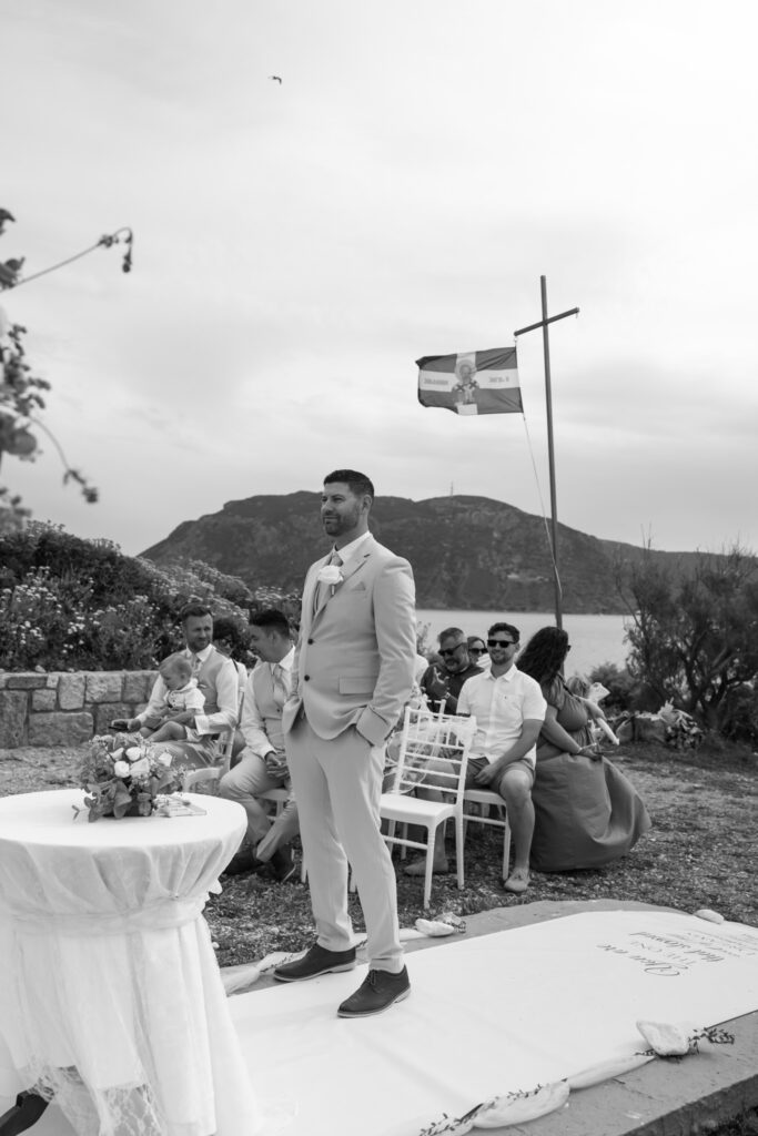 Groom waiting at the alter for his bride, black and white editorial photography, destination wedding at Agios Stephanos, Kastri island in KOS, Greece