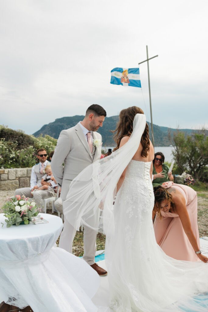 Groom waiting at the alter for his bride, editorial photography, destination wedding at Agios Stephanos, Kastri island in KOS, Greece. Groom wearing light beige suit and baby pink tie.