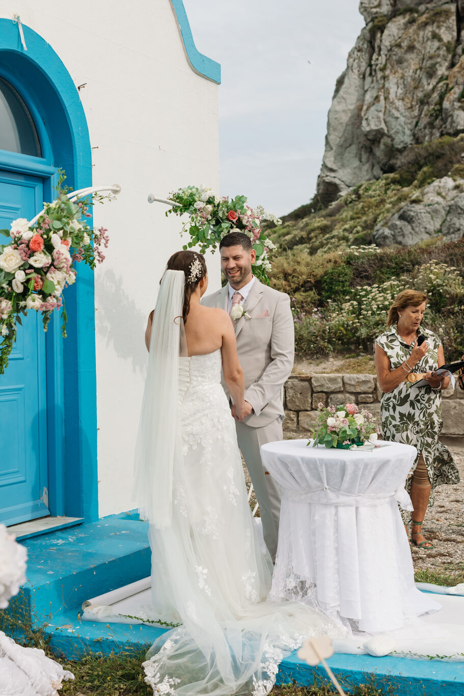 Outdoors island wedding ceremony, editorial photography, destination wedding at Agios Stephanos, Kastri island in KOS, Greece. Blue and White chapel.
