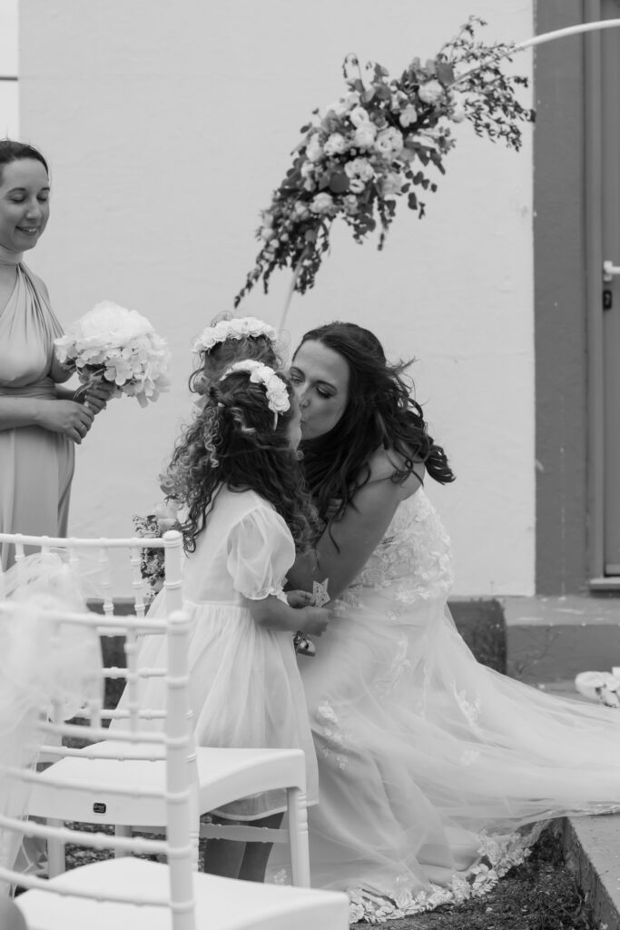 Outdoors island wedding ceremony, editorial photography, destination wedding at Agios Stephanos, Kastri island in KOS, Greece. Bride kissing her daughter.