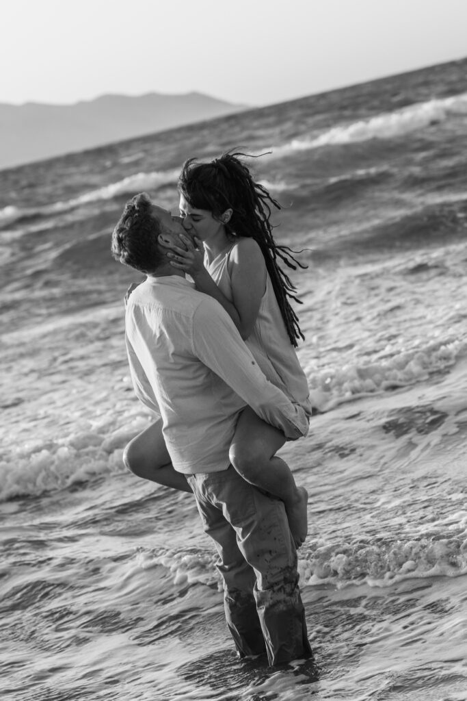 Romantic storytelling portrait of Greek and Italian couple walking barefoot on Kos beach at golden hour — destination wedding photographer Greece. Editorial photography, engagement beach sunset session.