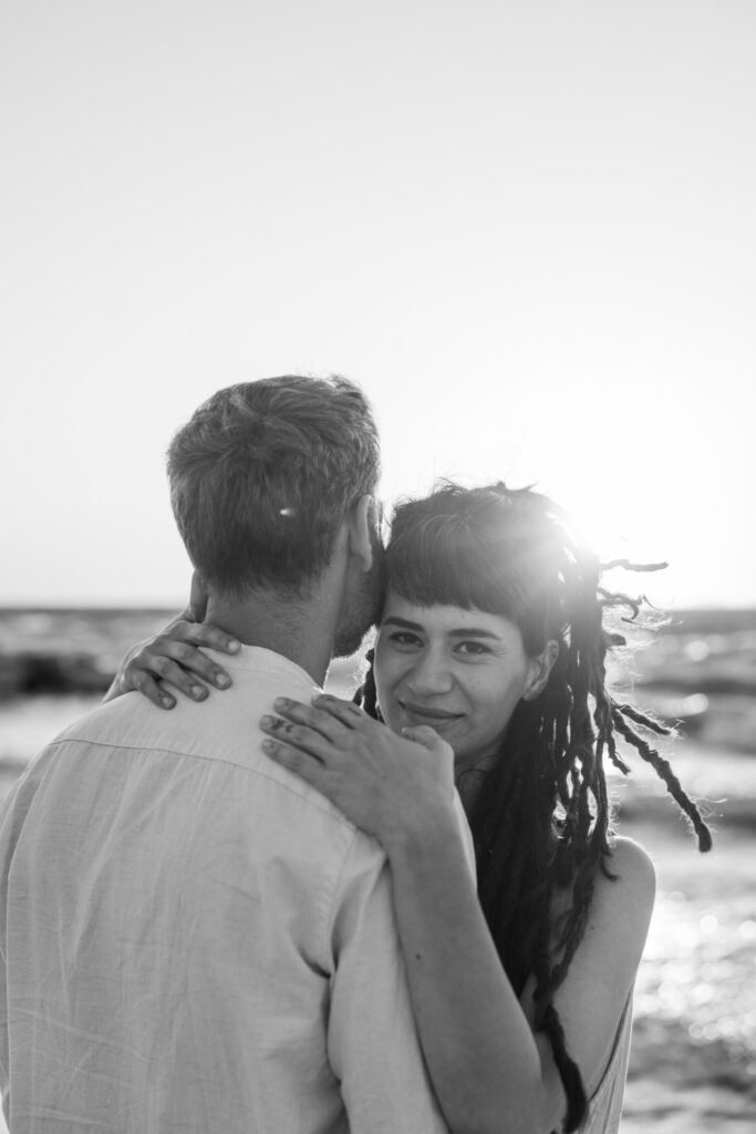 Romantic storytelling portrait of Greek and Italian couple walking barefoot on Kos beach at golden hour — destination wedding photographer Greece. Editorial photography, engagement beach sunset session.