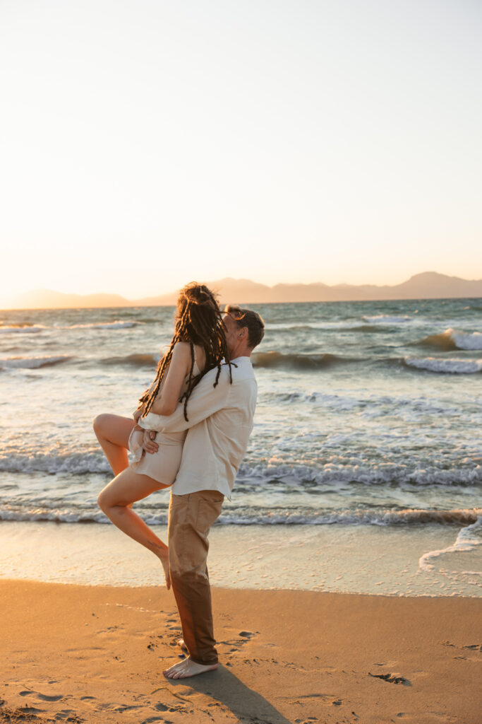 Romantic storytelling portrait of Greek and Italian couple walking barefoot on Kos beach at golden hour — destination wedding photographer Greece. Editorial photography, engagement beach sunset session.