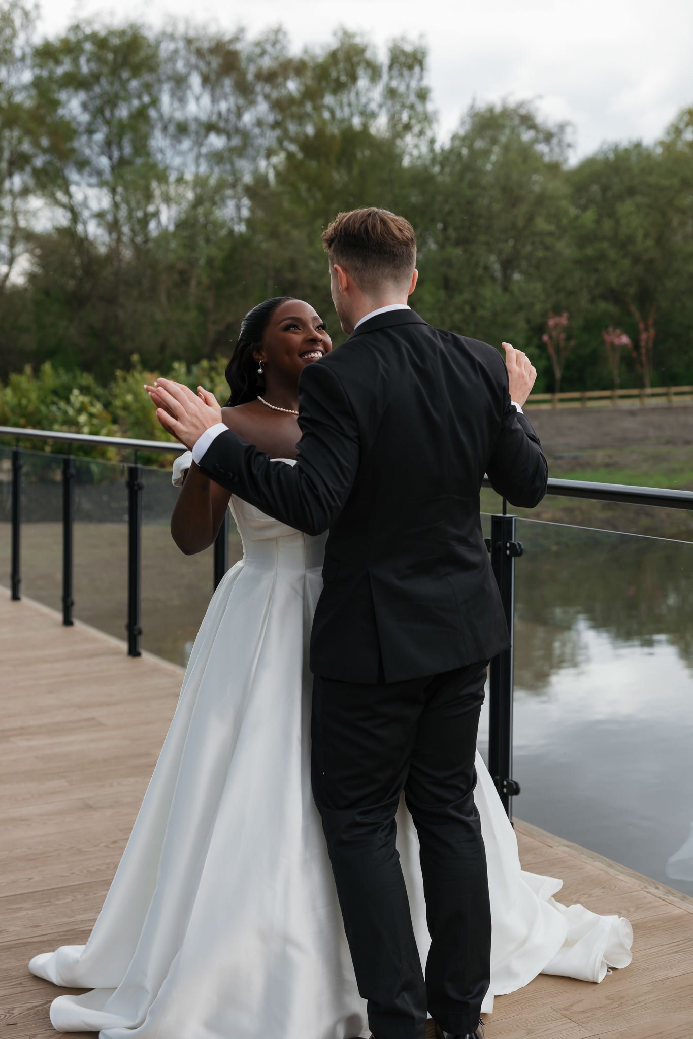 Editorial wedding photography — Black bride and White groom laughing together during lakefront portraits at Whistle Barns, multicultural interracial wedding